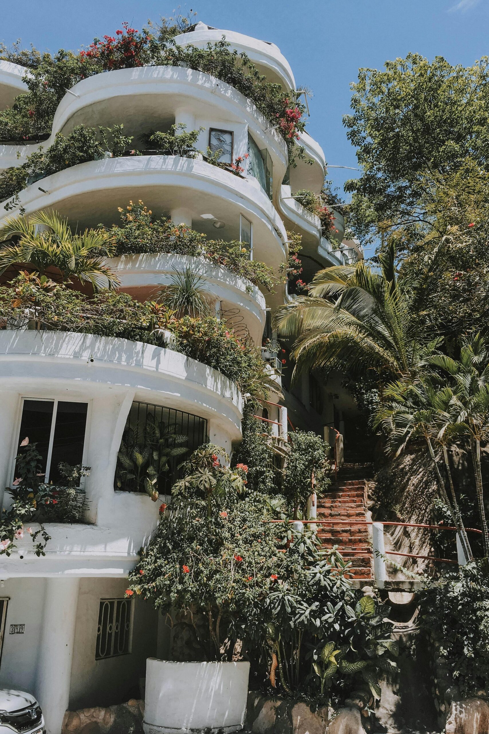 An apartment building filled with greenery on its every balcony.