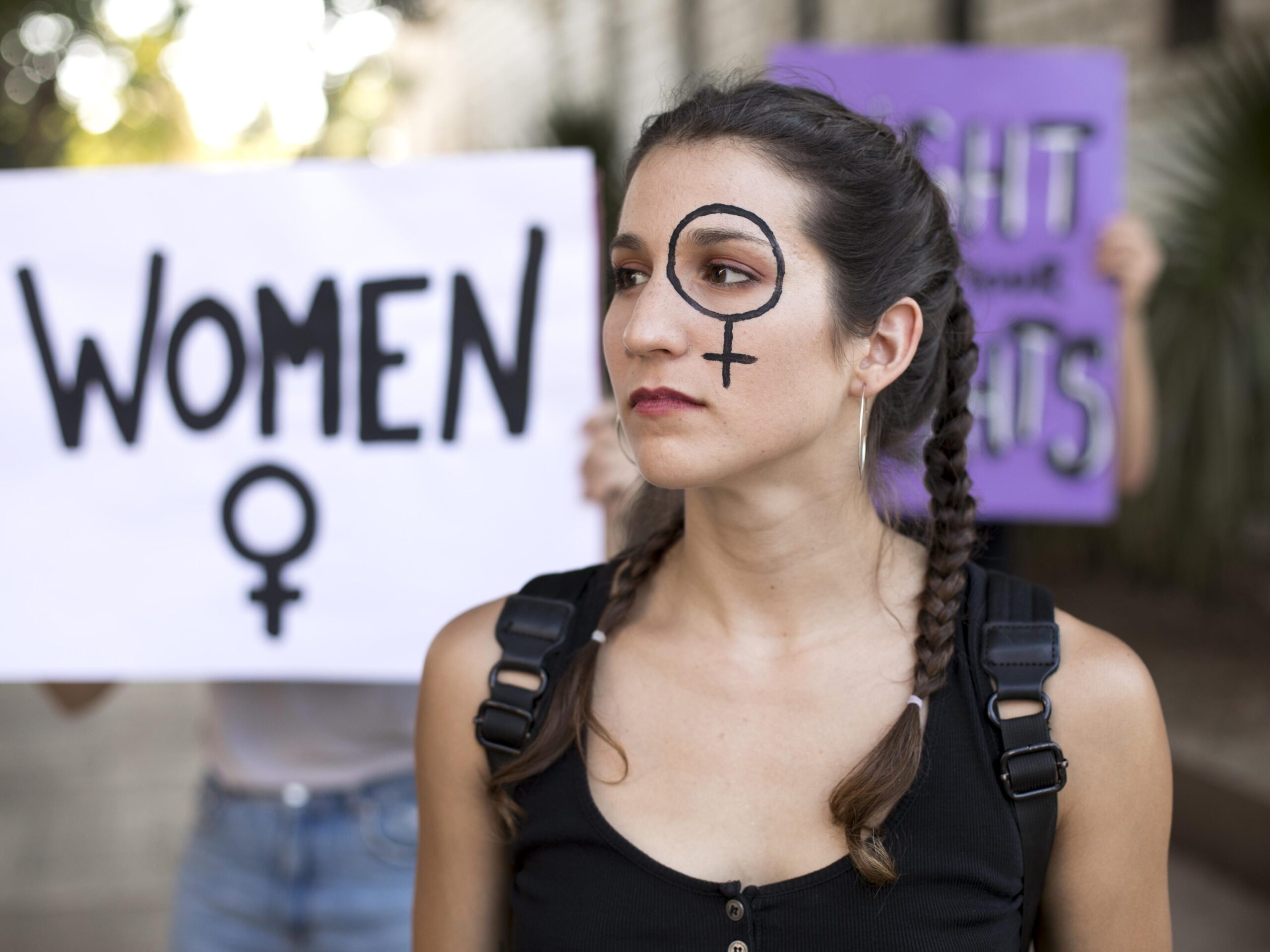 A protesting woman with a feminie symbole drawn on her one eye.