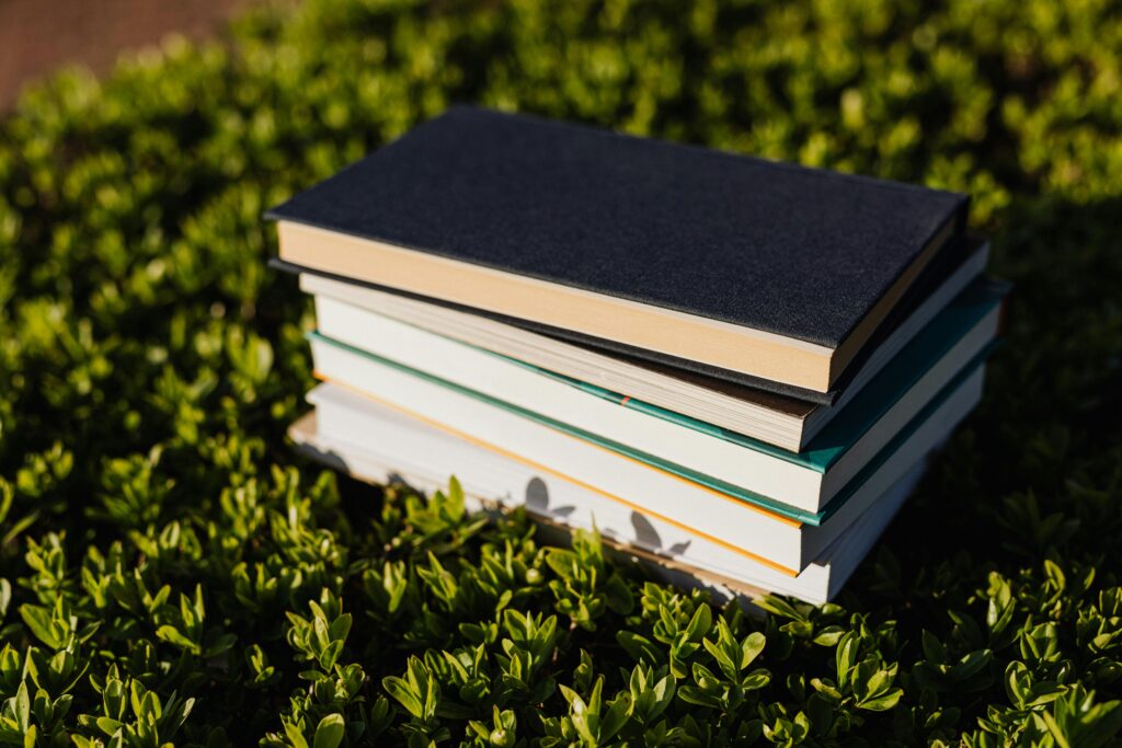 Pile of books on green grass representing eco-literacy in education.
