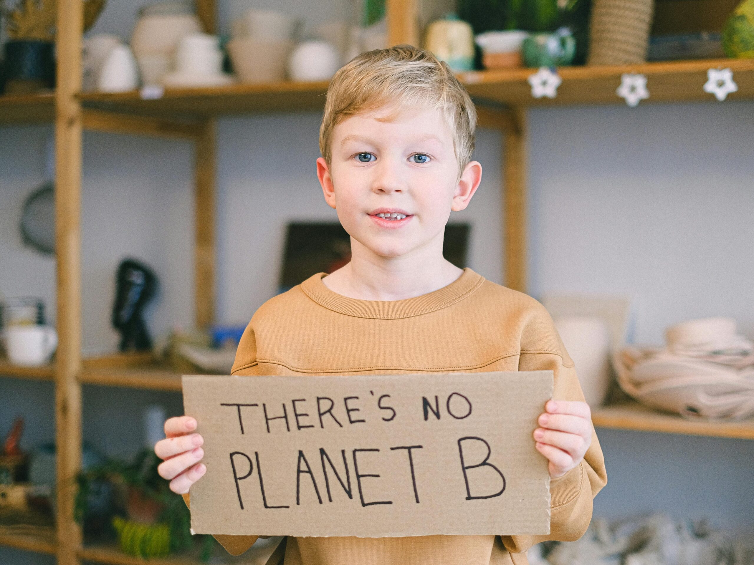 A boy pleading with a smile on his face and a cardboard saying, "there is no planet B."
