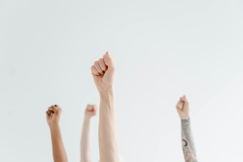 A group of diverse hands raised in solidarity, representing unity and empowerment.