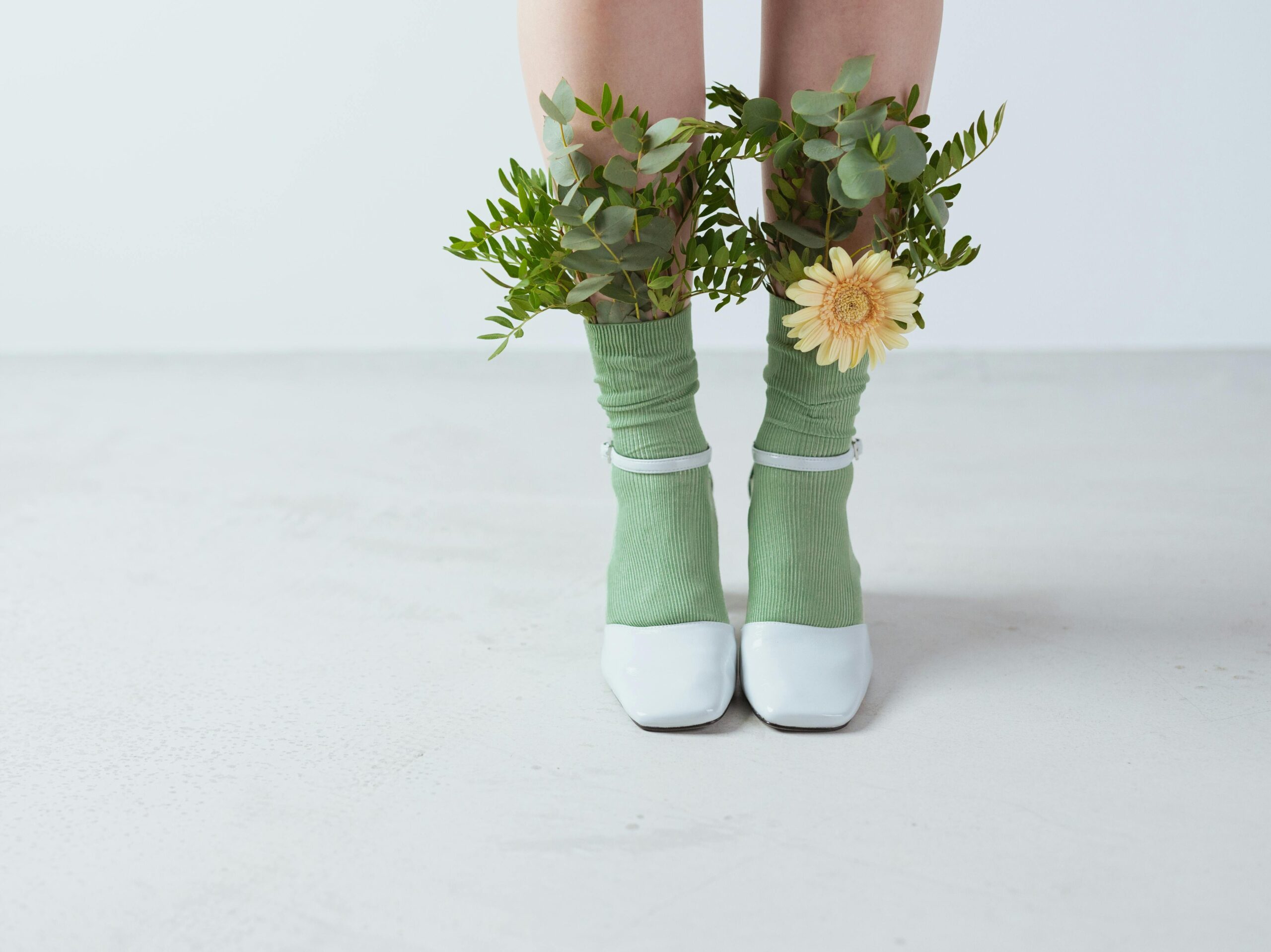 Creative display of eco-friendly fashion with green socks and floral artistic arrangement in a studio setting.